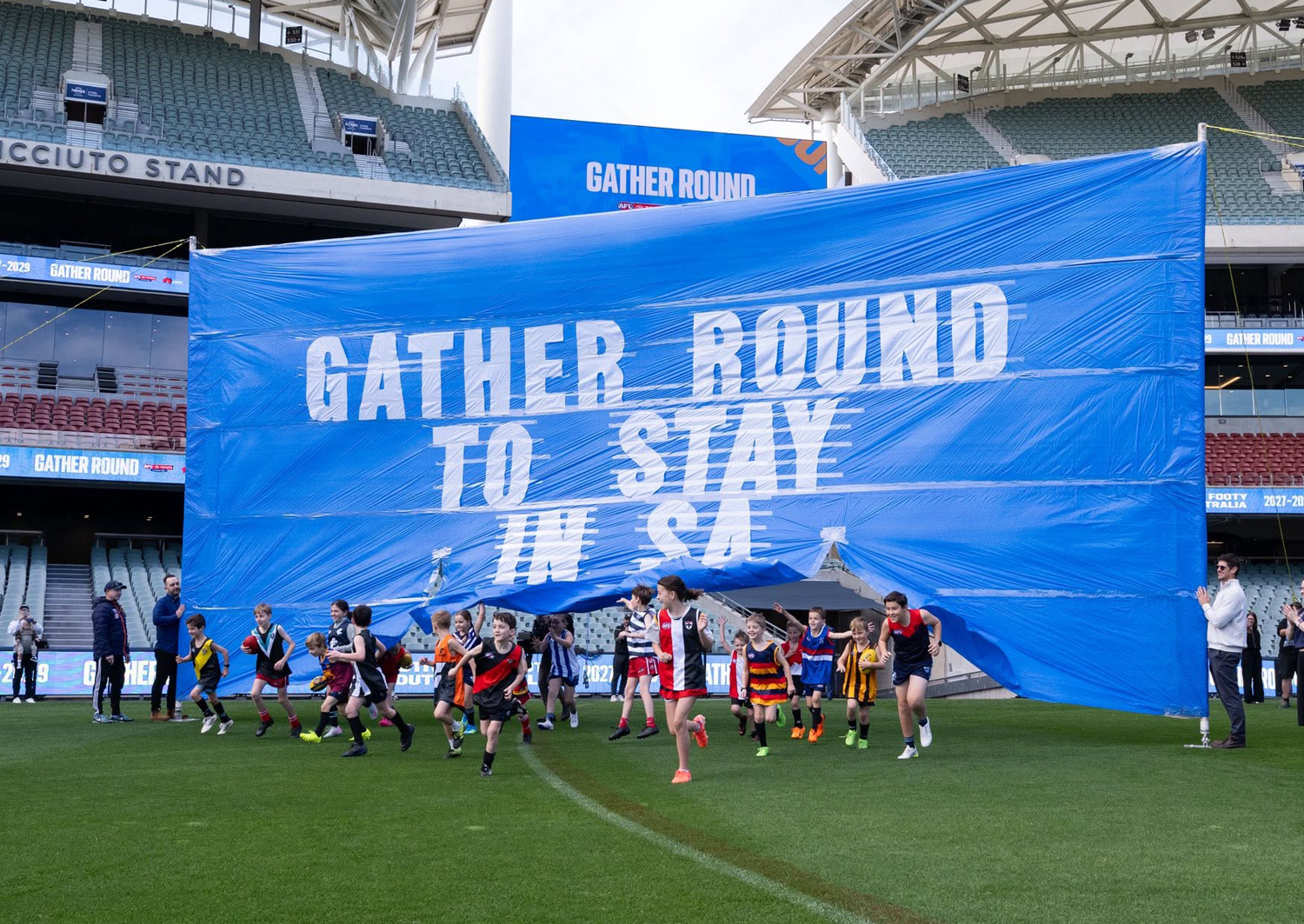 Children running through a Gather Round banner