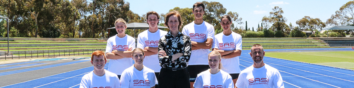 Keren Faulkner surrounded by athletes on a blue athletics track