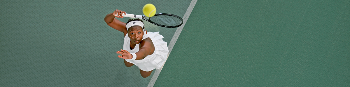 Female tennis player looking up a ball as she serves on the base line