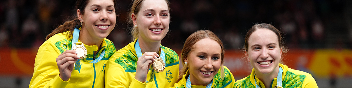 Four female athletes holding up gold medals