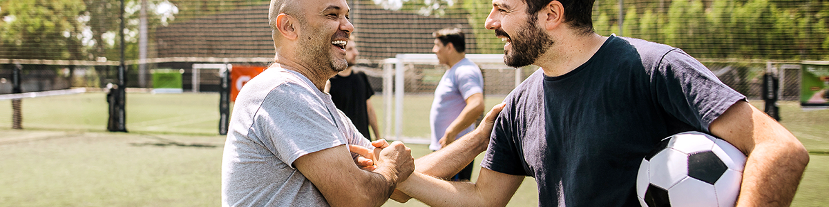 Two men shaking hands while one holds a soccer ball