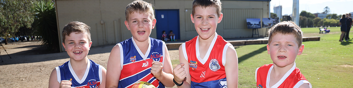 Children standing and smiling with footballs