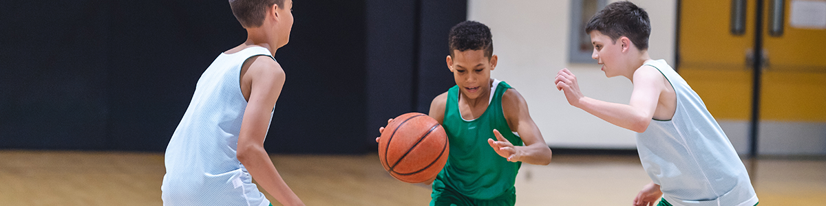 Three boys playing basketball on an indoor court