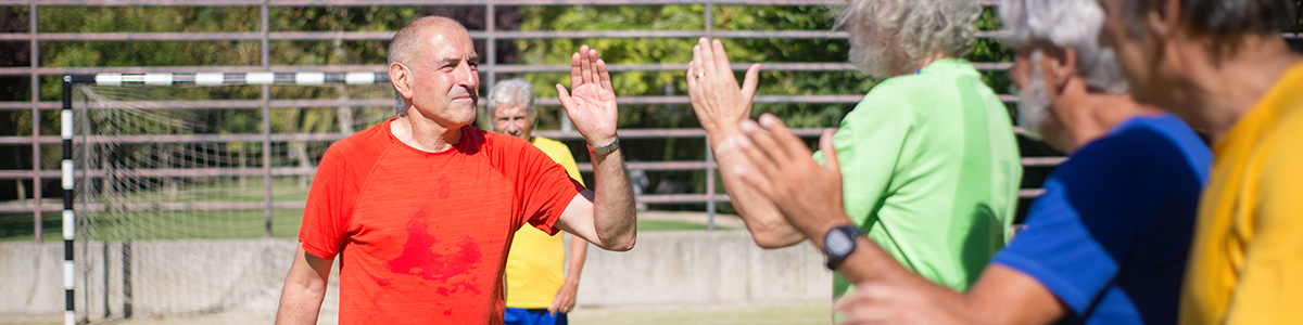 Active senior men high-fiving each other on a football field