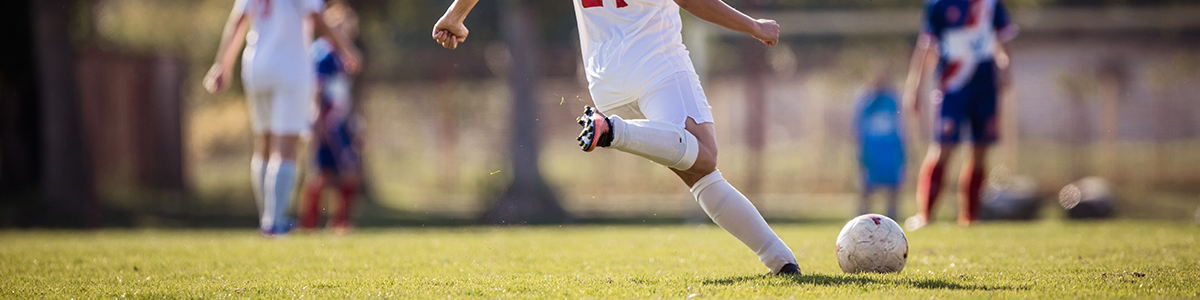 Female soccer player on the pitch about to kick a soccer ball