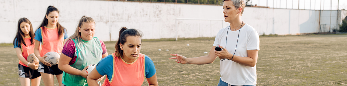 Coach holding a stop watch while players run past with a ball