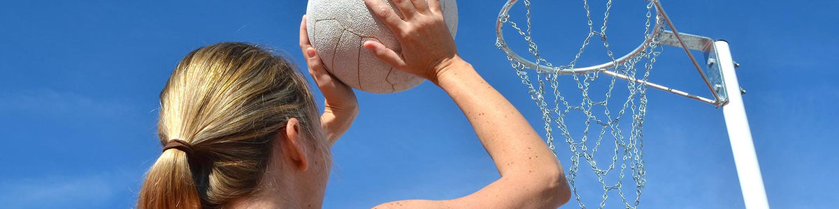 Girl aiming to shoot a netball towards a netball ring