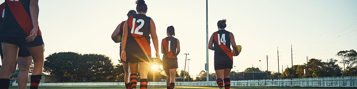 Female football players walking on a football oval
